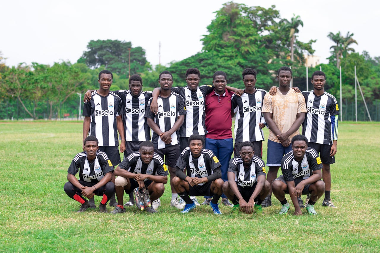 Youth soccer team in black and white jerseys posing together on a grassy field outdoors.